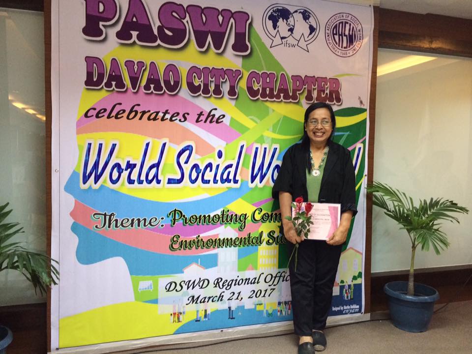 Social worker standing in front of a poster for World Social Work Day 2017 in the Philippines